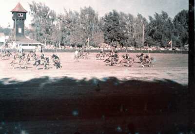 Plano general de un grupo de hombres uniformados a caballo portando banderines visto desde el sector de las gradas