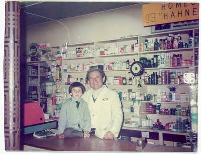 Eduardo Fernández Veas posa junto a su nieto Matías Reyne Fernández en el mostrador de la Farmacia Fernández de Río Bueno