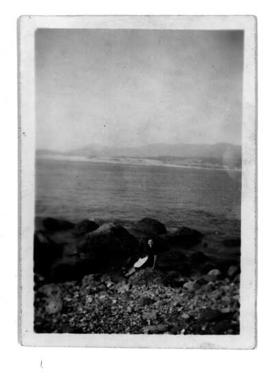 Mujer sentada en las rocas en la bahía, con el mar detrás