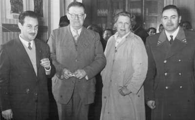 Retrato de plano medio largo de tres hombres y Olga Boettcher posando a la cámara. Están reunidos en el interior de la municipalidad durante una celebración