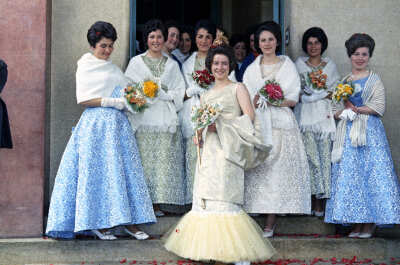 Retrato de plano entero de un grupo de Mujeres, entre ellas se encuentra Nora Manzano, Domínica Carrasco y Loreta Ferrón, posando de frente con un ramo de flores en las manos. Se encuentran en la actual entrada de Urgencias del Hospital Juan Morey de La Unión