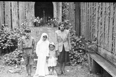 Plano general de una mujer joven, dos niñas y un niño posando frente de pie frente a un altar