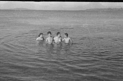 Plano general de tres mujeres y un hombre dentro de un lago.