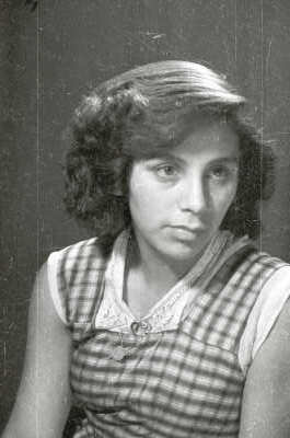Retrato de estudio de Plano medio de una mujer joven, posando sentada de Medio perfil. Lleva puesto un prendedor en el cuello de su Vestido