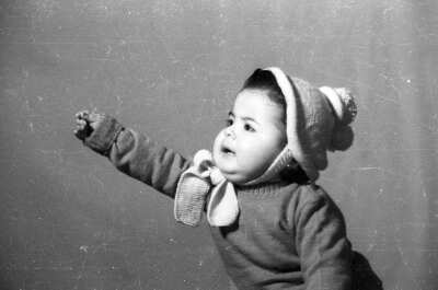 Retrato de estudio de Plano medio de un niño de temprana edad, posando sentado de Medio perfil mientras estira su brazo hacia un costado