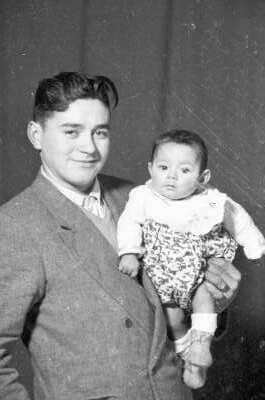Retrato de estudio de Plano medio de un hombre de Traje sonriendo mientras posa con una Bebé en brazos