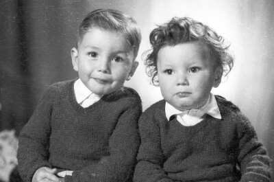Retrato de estudio de Plano medio de un niño y un bebé posando sentados mientras miran de frente hacia la cámara