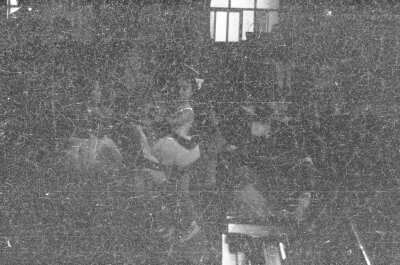 plano general de un grupo de niñas, caracterizadas como bailarinas de ballet, realizando una presentación artística. Se encuentran en una estructura no identificada. Fotografía oscura