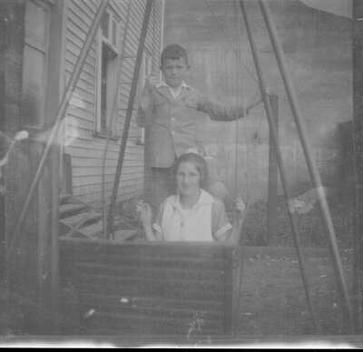 Plano medio de dos personas, un niño y una adolescente, posando en un juego en el patio de una casa