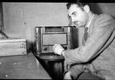 Plano medio de un hombre adulto sentado sintonizando una radio